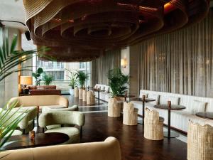 a lobby with tables and chairs and a large ceiling at Pullman Quay Grand Sydney Harbour in Sydney