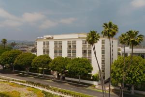 a white building with palm trees in front of a street at L'Ermitage Beverly Hills in Los Angeles