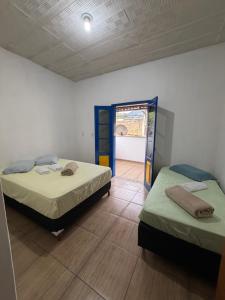 two beds in a room with a door open at Villa Jardineira in Ouro Preto