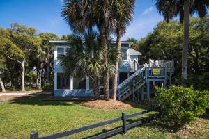 a blue house with a staircase leading to a yard at Rich Tymes in Edisto Island