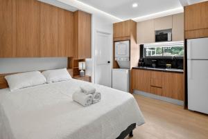 a bedroom with a large white bed and a kitchen at Hotel Sabana Inn in San José
