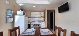 a kitchen with a wooden table with two wine glasses on it at Cabañas Paso de Viento in El Chalten