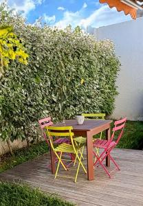a wooden table with four colorful chairs around it at Nouméa F2 jardin et clim, proche plages in Noumea