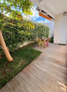 a patio with a table and chairs next to a hedge at Nouméa F2 jardin et clim, proche plages in Noumea