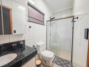 a bathroom with a shower and a toilet and a sink at Casa em bairro nobre + 3 quartos com ar e 2 vagas in Ourinhos +31 photos
