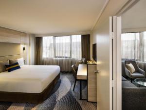 a hotel room with a bed and a desk at Novotel Sydney Parramatta in Sydney