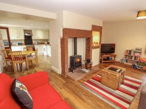 ein Wohnzimmer mit einem roten Sofa und einem Kamin in der Unterkunft The Old Bothy in Wigton