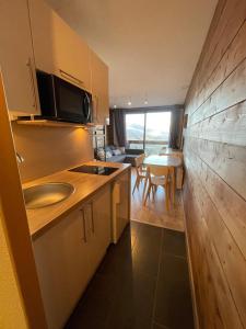a kitchen with a sink and a table in a room at appartement cozy au pied des pistes in Le Corbier