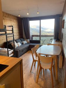 a living room with a table and chairs and a couch at appartement cozy au pied des pistes in Le Corbier