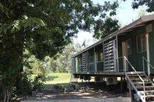une cabane verte avec un porche et un arbre dans l'établissement Corroboree Park Tavern, à Marrakai