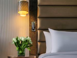 un jarrón de flores en una mesa junto a una cama en The Artisan Hotel Istanbul - MGallery Collection, en Estambul