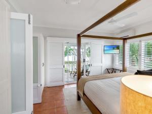 Un dormitorio con una cama en una habitación con ventanas. en The Reef House Adults Retreat - Enjoy 28 Complimentary Inclusions, en Palm Cove