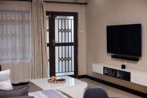 a living room with a flat screen tv and a couch at Palms & Pebbles Home in Lilongwe