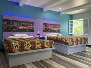 2 camas en una habitación con paredes azules y moradas en Fountain Inn Motel - Alhambra, Los Angeles, en Alhambra