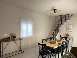 a dining room with a table and chairs and a staircase at Casa Terrones - Espacio, Barbacoa, Centro ciudad y Sierra Nevada a un paso in La Zubia