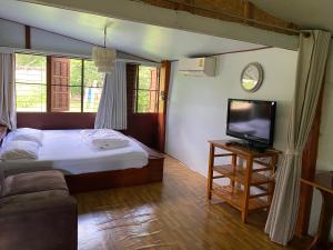 Un dormitorio con una cama y un televisor de pantalla plana. en Baanpak Chomdoi, en Nan