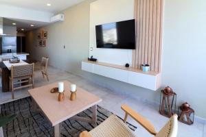 uma sala de estar com uma televisão e uma mesa e cadeiras em Beautiful and New Bahía Serena Condominium em Isla Cardones