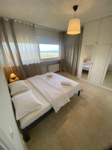 a bedroom with a large white bed with a window at Aegean Hill Retreat in Neos Voutzas