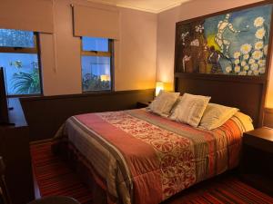 ein Schlafzimmer mit einem Bett und einem Gemälde an der Wand in der Unterkunft Hostal Boutique 180 Grados in Algarrobo