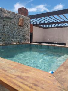 a large swimming pool with a stone wall at Casa Pitanga Flat in Jericoacoara