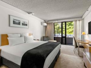 a hotel room with a large bed and a desk at Novotel Queenstown Lakeside in Queenstown +100 photos