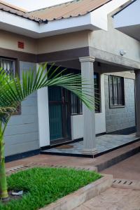 a house with a palm tree in front of it at Palms & Pebbles Home in Lilongwe