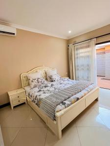 a bedroom with a large bed with a window at Palms & Pebbles Home in Lilongwe