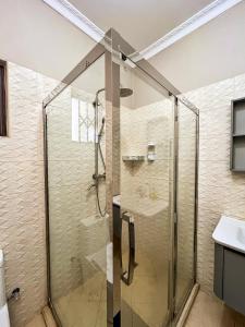 a shower with a glass door in a bathroom at Palms & Pebbles Home in Lilongwe