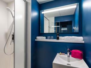 a blue bathroom with a sink and a mirror at ibis budget Epinal in Épinal +27 photos