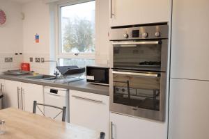 Una cocina con horno de acero inoxidable y una mesa. en Knightswood, en Scotstoun West Station 28 fotos más