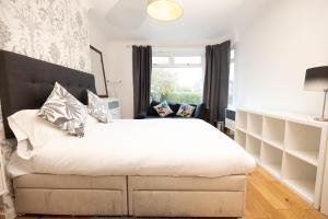 Un dormitorio con una gran cama blanca y una ventana. en Knightswood, en Scotstoun West Station