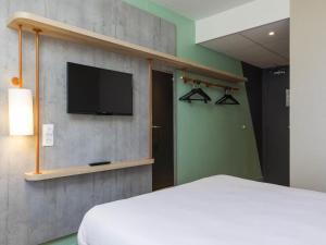 Un dormitorio con una cama y un televisor de pantalla plana. en ibis budget Senlis, en Senlis 39 fotos más