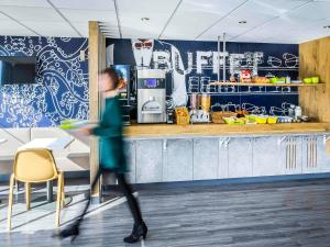 een persoon die langs een aanrecht in een keuken loopt bij Ibis Budget Fréjus St Raphaël centre in Fréjus