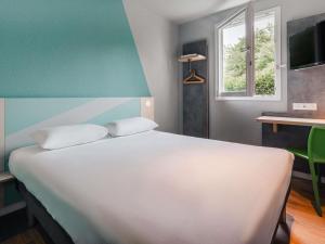 a bedroom with a large white bed and a window at ibis budget Rennes Route de Saint Malo in Montgermont +96 photos