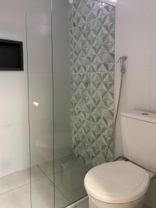 een badkamer met toilet en glazen douche bij Apartamento Paraíso Refúgio - Manoah Beach Flats in Maragogi +50 foto's