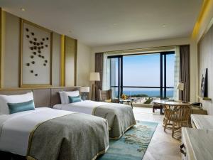 two beds in a hotel room with a large window at Sofitel Sanya Leeman Resort in Sanya