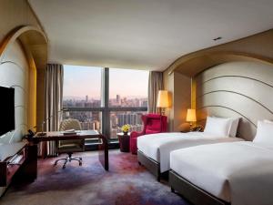 a hotel room with two beds and a desk and a window at Sofitel Kunming in Kunming