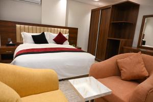 a hotel room with a bed and two chairs at ساتورن هاوس للشقق الفندقية in Tabuk
