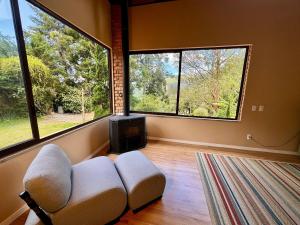a living room with a chair and two large windows at Casa com Jacuzzi e Área Gourmet em Mury in Nova Friburgo +64 photos
