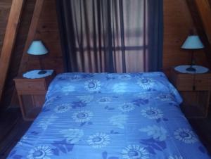 Una cama con un edredón azul con flores. en Paraje del Molino Casa Alpina, en San José