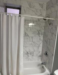 a bathroom with a white shower curtain and a tub at Weehawken Apartment NYC Skyline in Weehawken