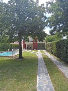 a walkway with a tree and a swimming pool at Nuestro Rinconcito in Villa Cura Brochero
