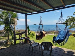 a porch with chairs and hammocks overlooking the ocean at Hostal Hilltop Capurgana in Capurganá