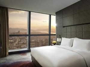 a bedroom with a large white bed and large windows at Sofitel Kunming in Kunming