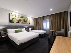 a hotel room with two beds and a table at Mercure Penrith in Penrith