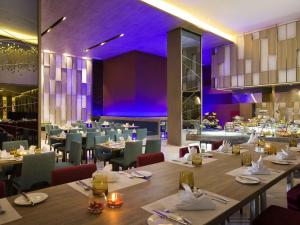 un restaurante con mesas, sillas e iluminación púrpura en Novotel Makassar Grand Shayla, en Makassar