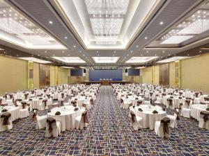 a large banquet hall with white tables and chairs at Grand Mercure Medan Angkasa in Medan +72 photos
