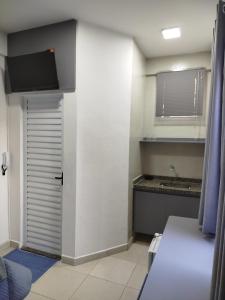 a room with a door and a kitchen with a sink at Vila Del Rei - Flat no Centro de São João Del rei in São João del Rei
