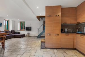a kitchen with wooden cabinets and a living room at Gîte Salgesh - 16 pers & 16 lits - Terrasse - Nature in Salgesch