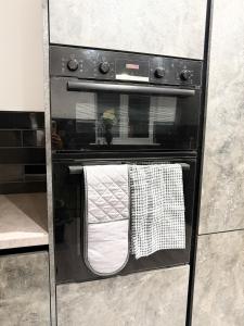Un horno negro con dos toallas colgando de él. en The Aurora Apartments, en Peterborough